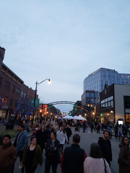 North High Street in Columbus, Ohio. All is closed off to car traffic, except for intersections to cross the street. Hundreds of people walk on a street that is normally reserved for cars.The arches above High Street are green, white, and red.