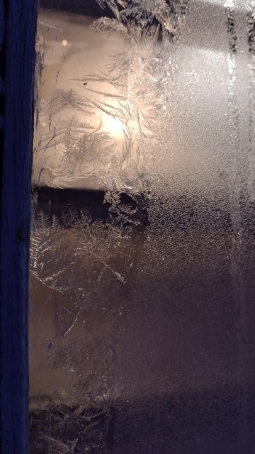 frosted patterns on the window, the light of the lamp visible behind the glass