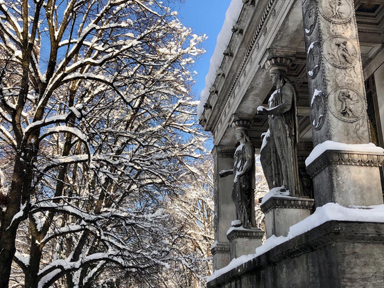 Centurion figures in columns with trees in the background, covered in snow, at Munich’s Friedensengel