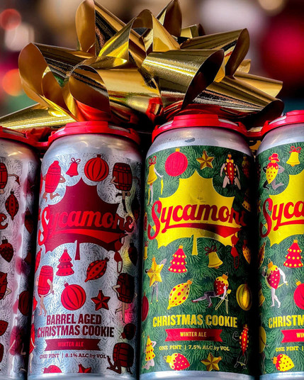 Cans of Christmas Cookie Ale and Barrel Aged Christmas Cookie Ale, two specialty winter ales from Sycamore Brewing of North Carolina. The photo from Sycamore's Facebook page also shows a large golden gift bow on top of the cans.