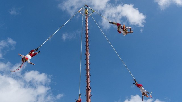 Acrobats suspended from a pole.