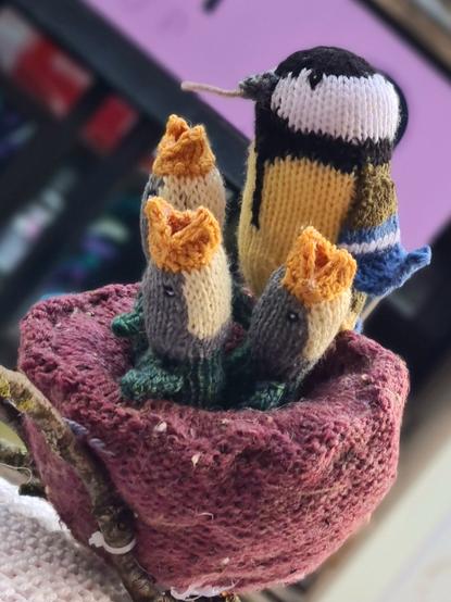 A knitted blue tit feeding its chicks on a post box topper.