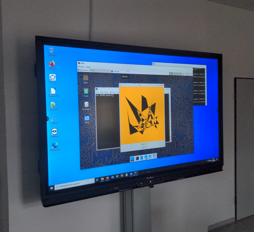 Großes Display einer digitalen Tafel zeigt den XFCE-Desktop eines Linux-Systems in einem Fenster der Virtualisierung QEMU unter MS Windows