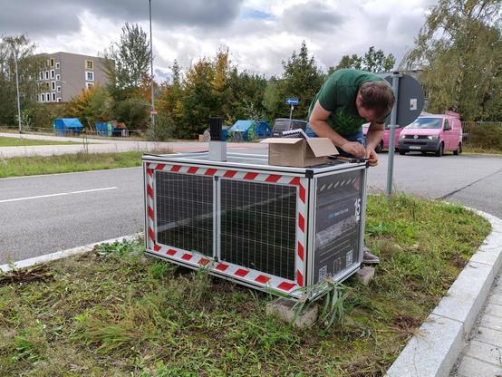 Colleage is working on a box next to the streets. He removes the top cover.