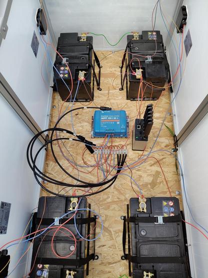 View inside the box. Four car batteries, charge controller, V2X node and solar panels.
