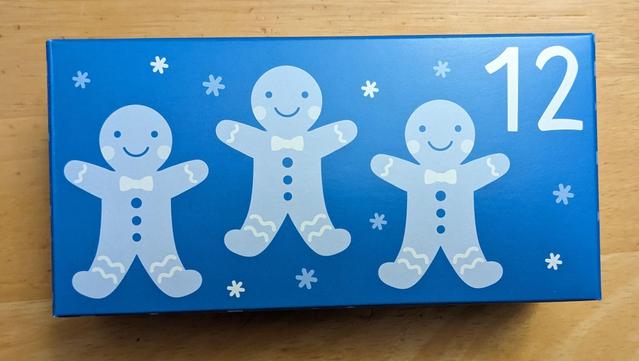 Long rectangular blue box with three gingerbread men across the front and the number 12 in the top right corner.