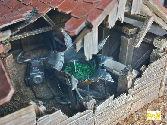 Close up of the hole in the wall of the hut, showing some chemical equipment and a tank burst open.