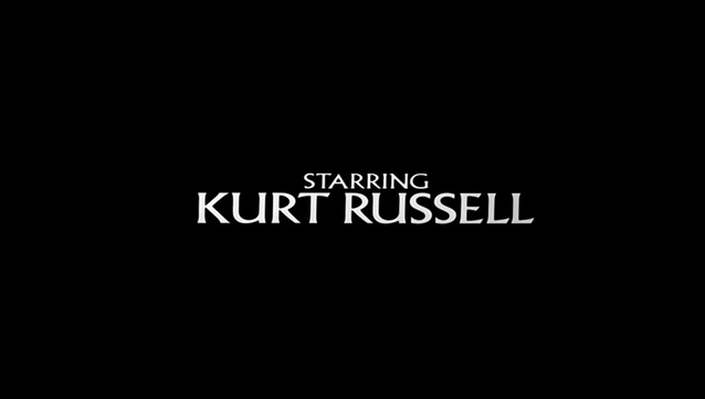 Una imagen de fondo negro con el texto "Starring Kurt Russell" en blanco, en una fuente elegante.  "Starring" está en una fuente más pequeña sobre el nombre del actor.