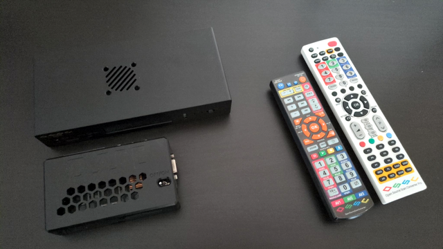 An OSSC Pro, normal OSSC and their remotes on a table for size comparison.