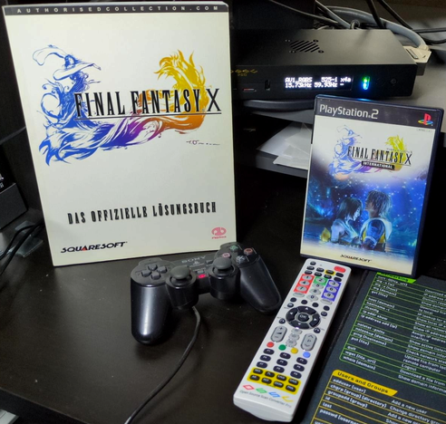 The official German Final Fantasy X guide, the NTSC-J PS2 version of Final Fantasy X International, a running OSSC Pro and its remote next to a PS2 controller.