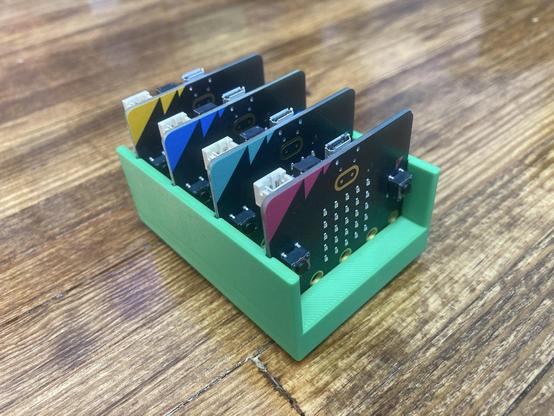 A 3D printed micro:bit holder with four micro:bit boards inserted into it.