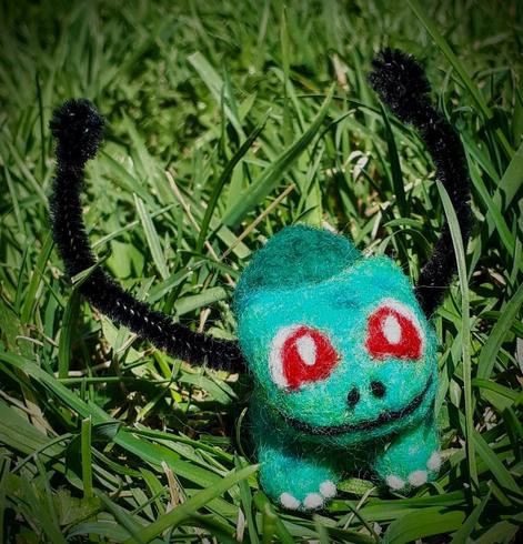 A needle felted Bulbasaur frolicking in the grass.