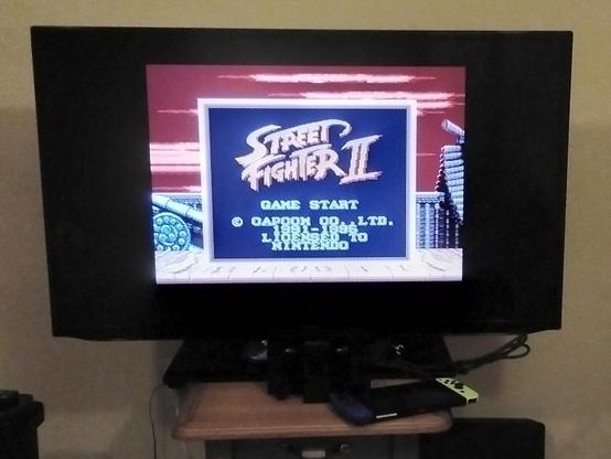 Photo of the title screen of Street Fighter 2, on Game Boy, on a large TV via the Analogue Pocket.