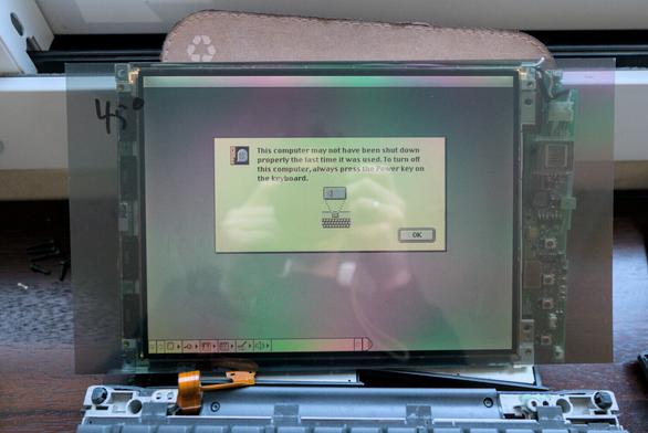 Photo showing the PowerBook's bare display turned on, with a polarizing filter loosely standing in front of it. The number "45°" is hand written in the top left hand side of the filter (on its protective film)
