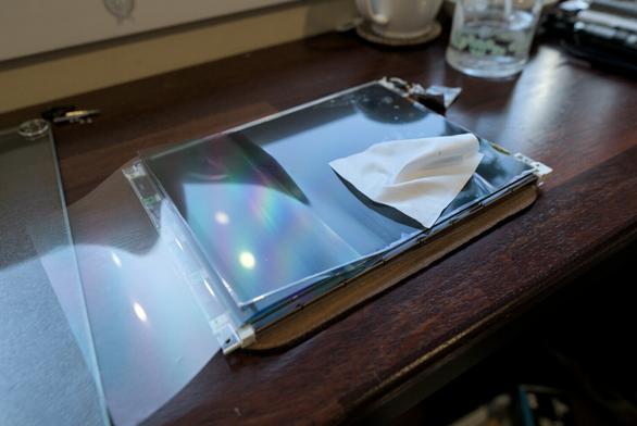 Photo showing the process of sticking on the new polarizing filter from right to left, with the left-hand side still unattached. A clean cloth is laying on top of the screen that I was using to apply (gentle) pressure when attempting to remove all the bubbles while attaching the filter.
