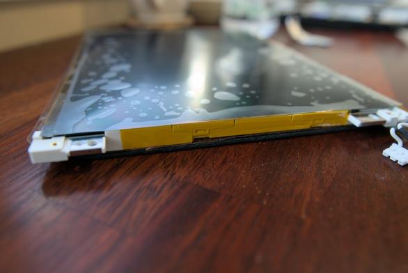 Photo showing a close-up of the side of the bare display, showing a strip of Kapton tape, keeping the new polarizing filter in place. The polarizing filter appears to show a lot of air bubbles, but that's just the top protective film of the filter itself, as I had to temporarily remove parts of it when attaching the Kapton tape.