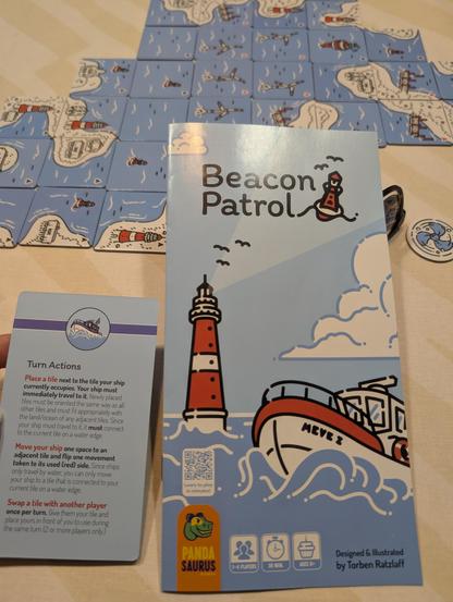 Beacon Patrol game, with a lighthouse and a boat on the cover; plus smaller tiles with water, land, windmills, buoys, lighthouses etc. on them.