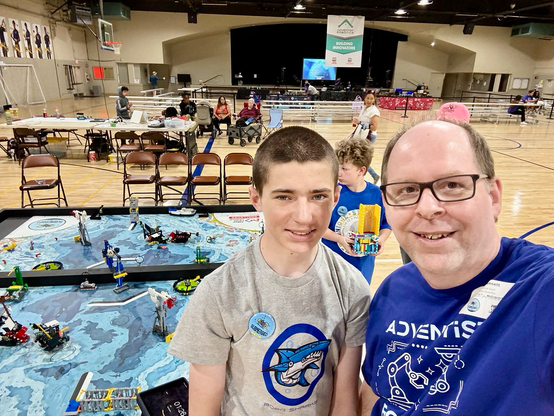 Selfie of me and my sister-in-law’s son with the Lego Robotic tournament area in the background.