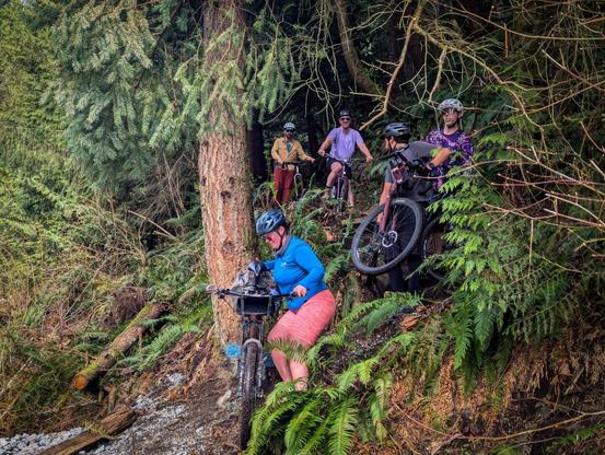 people with bikes are walking down a steep trail