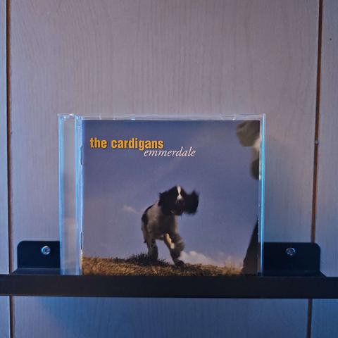 A CD case sits on a shelf. The front cover shows a blurry dog running towards to the camera