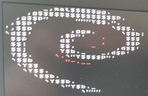 Photo of neofetch displaying Debian GNU/Linux logo rendered in text mode using Gnu Girl, a custom tiny 8×8 pixel console font by vrtxd. Black background, greenish ambient light, white text with red text highlights.