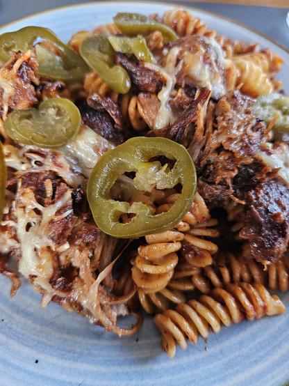 Das Bild zeigt eine appetitliche Portion Spaghettis mit Schinken und Jalapeños. Die Spaghetti sind rot und spiralförmig, bedeckt mit geschmolzenem Käse und zerkleinertem, braunem Schinken. Scharfe Jalapeños in Scheiben sind über das Gericht verteilt, was eine leichte Hitze hinzufügt. Der Käse ist leicht gebräunt, was auf eine gutes Backen oder Grillen hinweist. Das Gericht ist auf einem blauen Teller mit einem goldenen Rand serviert, der einen schönen Kontrast zu den warmen Farben des Essens bildet.

Bereitgestellt von @altbot, privat und lokal generiert mit Ovis2-8B