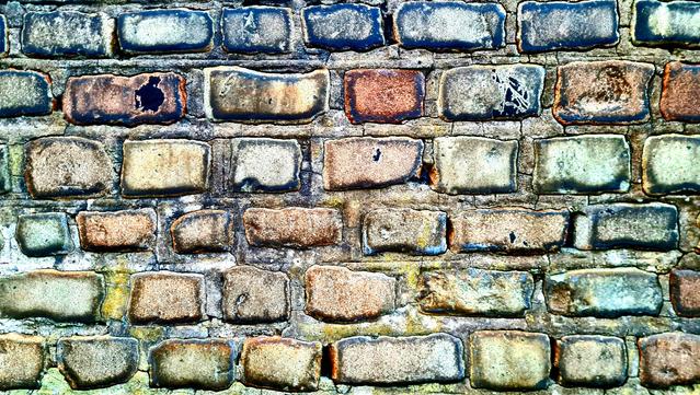 An old wall maxe up of uneven and weathered stones.
