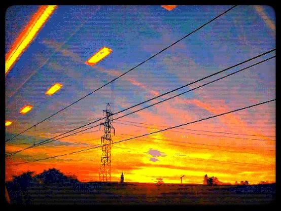 A low resolution stylized photograph of the sun rising over the canton of Aargau in Switzerland. Powerlines cross the sky with trees, a church tower and crane visible on the horizon. The image has a moody, cyberpunk feel.