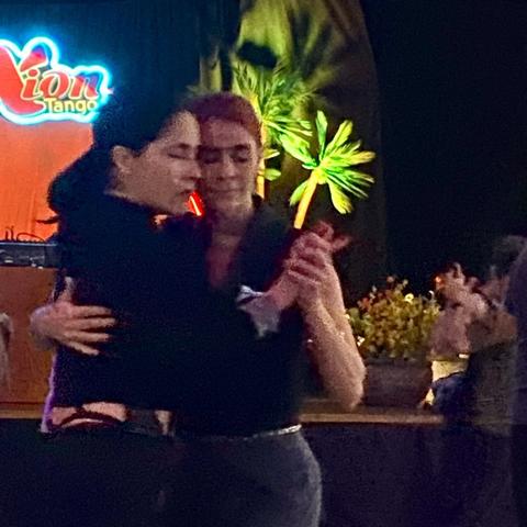 Two women, wrapped in each other’s embrace, dance cheek to cheek. They look like peaceful.