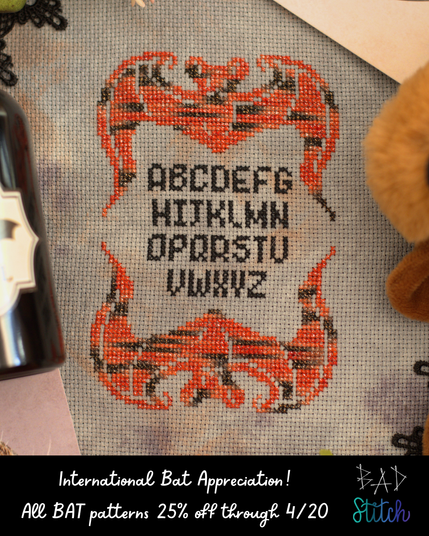 A cross stitch project of two mirrored bats with a small, pixel alphabet stitched between them. The stitcher used an orange and black variegated floss to stitch the design. International Bat Appreciation Day. All BAT patterns 25% off through 4/20. BAD stitch logo.
