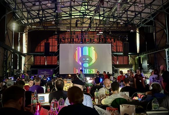 ANSI drawing of the Bitbear logo in rainbow colors shown on the big screen at Revision 2025.
