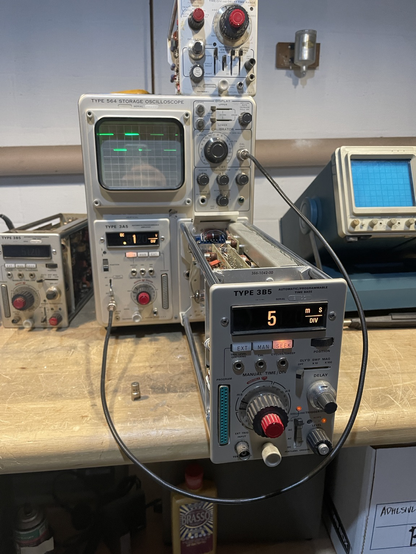 A 1960s oscilloscope with one of its plug-ins on an extender to place it out into a service position. A stable square wave trace is displayed, and the vertical deflection and sweep speeds are displayed via backlit numbers.