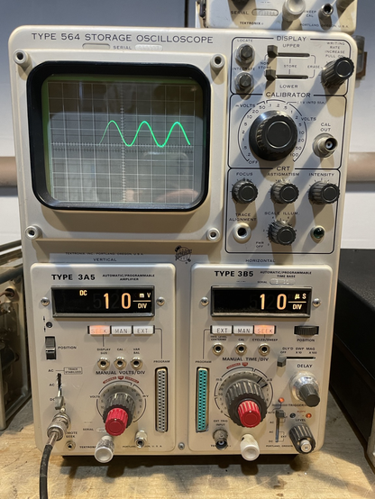 A sine wave shown at a higher frequency and sweep speed, the left portion of the waveform is faded, likely indicating that the unblanking signal is delayed or has a slow risetime.