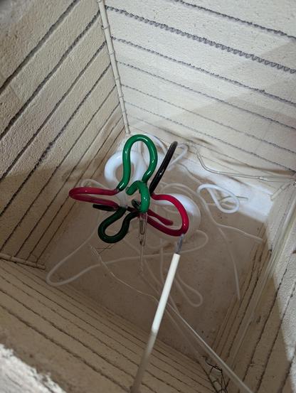 The doodle from before, now in the kiln, with a tube running up the side from its electrode.