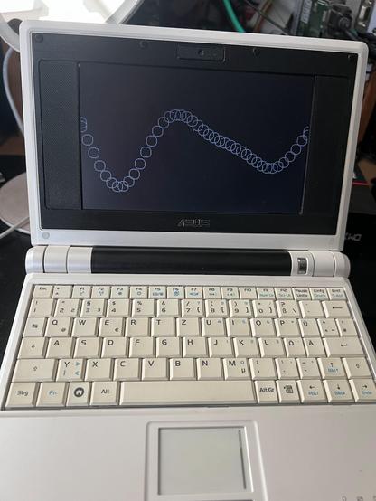 picture of an EeePC netbook with a black screen. There is a wave pattern drawn from unfilled white circles on the screen.