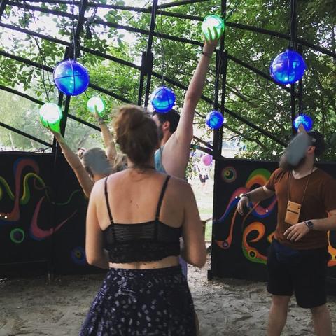 Colorful glowing balls hanging from above, people are connecting them with their hands