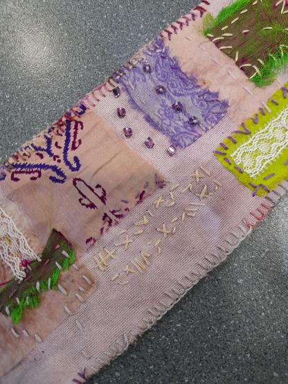 Detail with saree silk scraps, pseudo-letters (embroidered) and glass rocaille application. One silk scrap has beautifully printed ornaments, another an interesting weaving pattern. It's like a collection of my most beautiful textile scraps telling a story.