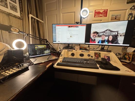 My desk with two monitors on a standing desk with ring lights and a laptop off to the right.