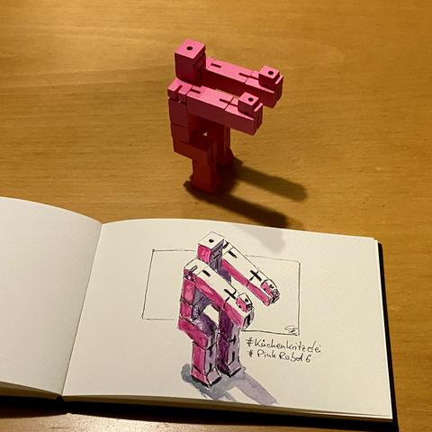 Watercoloured drawing of a pink wooden robot doing squats.
Above of the sketchbook with the drawing stands the original toy.