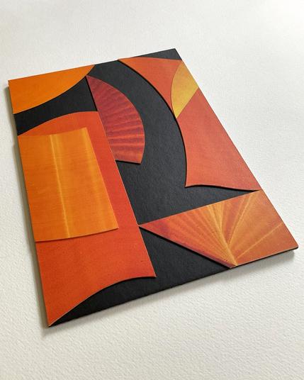 An angled photo of the collage art on a white background shows the light reflection.