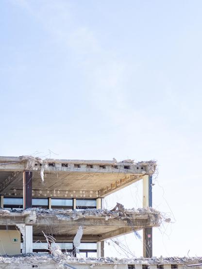 Foto: Schulskelett. Reste der alten Gesamtschule. Man sieht das übrig gebliebene Gerippe des alten Schulgebäudes vor klarem Himmel. Alles leicht überbelichtet.