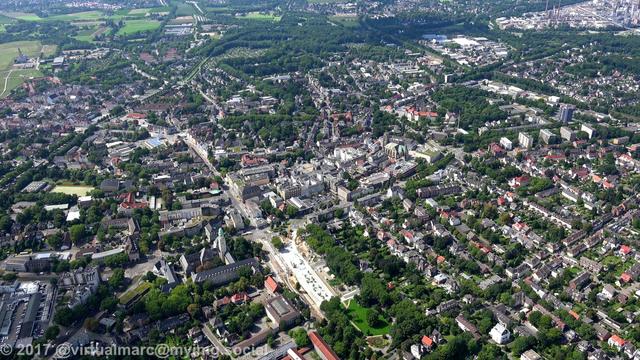 An aerial photo of Gelsenkirchen with many green places and trees between the houses.