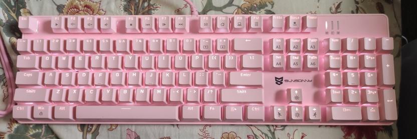 A mechanical keyboard that is all pink. White led lights shine through the letters.