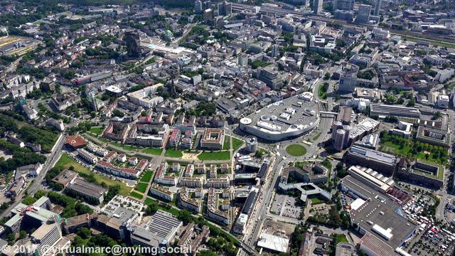 An aerial photo of the center of Essen.
You can see the Limbecker place, a big mall in the center of Essen.
Directly right of it is the CinemaxX Essen, it's Germanys biggest Multiplex Cinema with 5067 seats in 16 halls.
Below you see the buildings of the Funke Media Group next to the "new middle" living quaters.
In the top you can see the Essen Central station.
The black Y-Shaped building in the top left is the city hall of Essen.
In the top right of the city hall you can see the old synagogue.