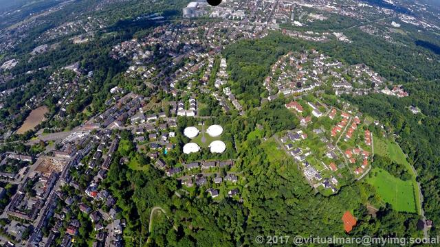 An aerial photo of Essen Bredeney. You can see multiple living quaters sourrounded by many trees. There are four silos in the middle of the image.