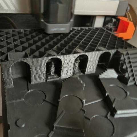 Imprimante Anycubic Kobra 3 en train d'imprimer un objet noir faisant toute la plaque de l'imprimante.