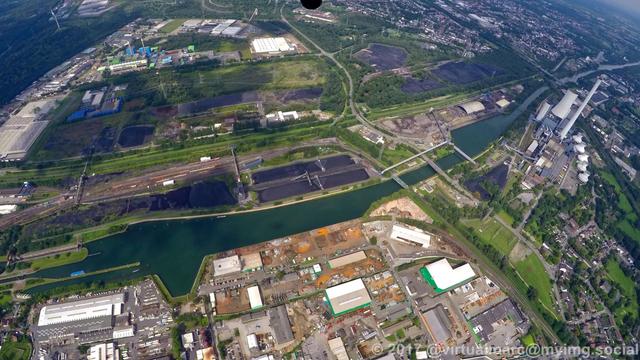 An aerial view of the Rhine-Herne Canal and the Emscher. Between the canal and the river are coal stocks. The Waste-fired power plant of Herne can be seen in the back.