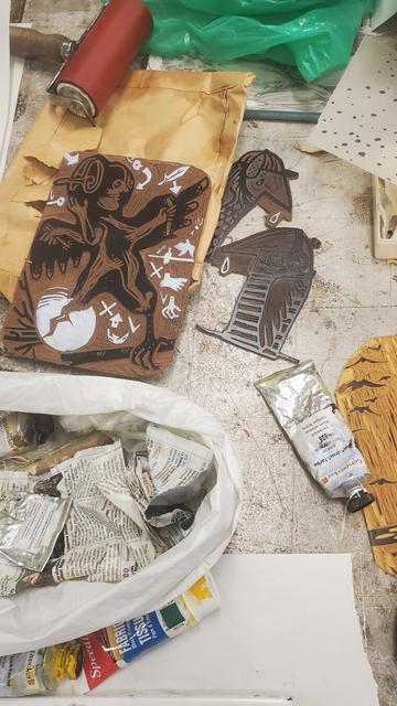 Photo de la table de travail avec plaques de lino encrées, tubes d'encre et rouleau