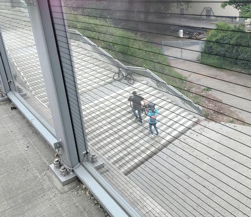 Ältere Radfahrer schleppen zu zweit ihre E-Bikes eine Treppe hoch.