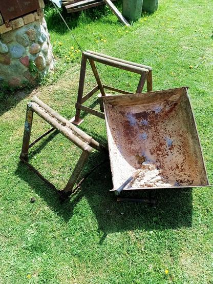 Scrap BBQ parts we had laying around the farm. There's two rusty old stands for parking a harrow on (one had to be levered out of the ground first and the harrow suspended on something else). They're not the same height. And a trough welded from three thick steel pieces. Somebody has previously abused it for mixing concrete, which needed chiseling out. A chisel rests inside and some concrete debris.